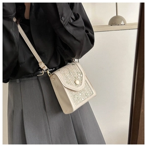 Detail view of woven straw crossbody bag with floral embroidery and textured finish