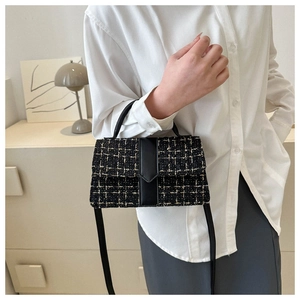 Detail of elegant black tweed crossbody bag with golden threads and leather handle