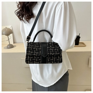 Detail of tweed checkered crossbody bag with black leather straps and metal buckle