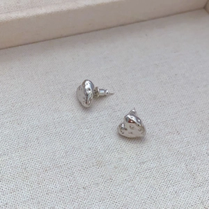 Detail view of heart stud earrings with hammered texture and 18k gold plated finish