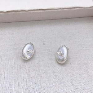 Oval silver stud earrings featuring a delicate 3D relief rose on matte textured fabric