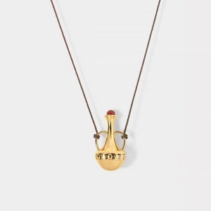 Close-up of vintage gold amphora pendant with red agate inlay on woven necklace cord