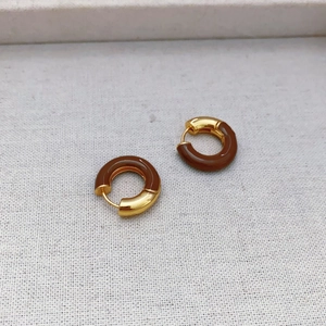 Detailed close-up of French-style gold-plated enamel hoop earrings on linen cloth