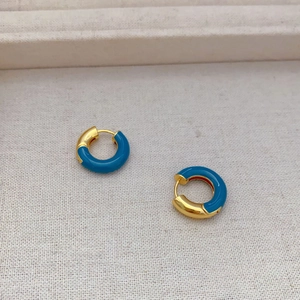 French style gold plated hoop earrings with blue enamel finish on a beige fabric background