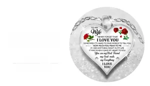 Macro view of heart-shaped glass pendant featuring red roses and message to wife