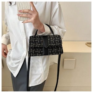 Close-up of elegant black tweed crossbody bag with refined leather strap and top handle