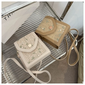 Detail of straw woven bags featuring floral embroidery and round snap closures