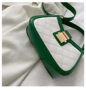 Detail view of the quilted white panel and green leather stitching on the shoulder bag