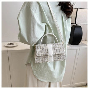 Detail of tweed crossbody bag with white faux leather trim shown on a model