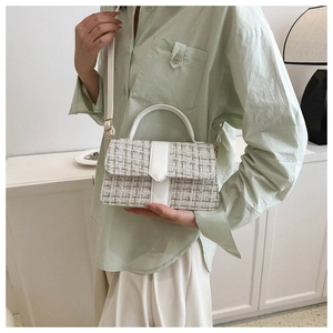 Woman in light green shirt carrying a white tweed crossbody bag in a minimalist setting