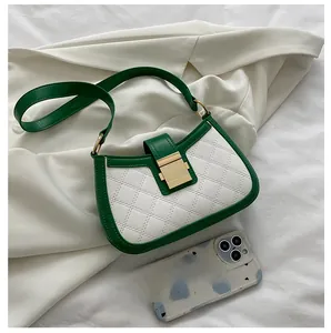 Detail showing white and green quilted leather shoulder bag next to a smartphone for scale