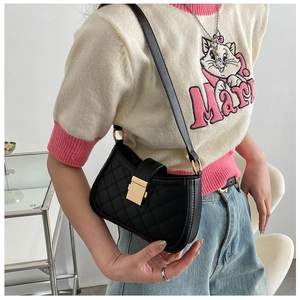 Detail of black quilted shoulder bag with gold square buckle and adjustable strap