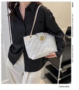 Borsa tote trapuntata bianca con catena dorata indossata da modella in ambiente sobrio