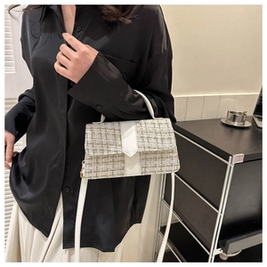Detail of tweed texture and white leather strap on the elegant crossbody handbag
