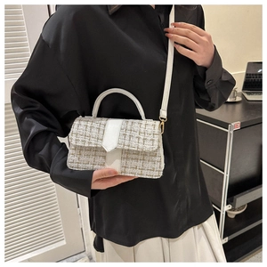 Close-up of white tweed handbag with gold hardware and elegant leather top handle
