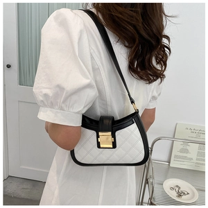 Detail shot of black and white contrast leather shoulder bag with gold square clasp buckle