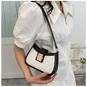 Detail of black and white quilted shoulder bag with gold rectangular clasp and chain