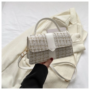 Detail of white tweed handbag with gold thread texture and adjustable leather shoulder strap