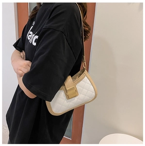 Detailed view of cream and caramel contrast shoulder bag with diamond quilting and gold buckle