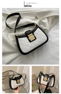Detail of black and white leather crossbody bag featuring a golden buckle and quilt texture