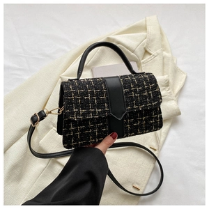 Close-up of black and gold tweed crossbody bag with leather handle and adjustable strap