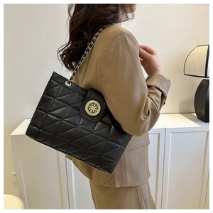 Dettaglio della trama a rombi trapuntata e fibbia dorata sulla borsa shopper nera