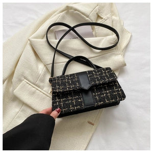 Detailed texture of black and gold tweed small square bag with leather handle and strap