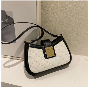 Close-up of contrast stitching and gold buckle on a black and white quilted shoulder bag