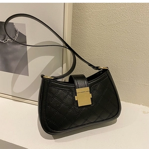 Detailed view of black quilted leather shoulder bag with gold square metal lock and strap