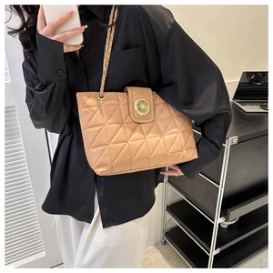 Borsa tote trapuntata kaki con chiusura dorata indossata da una modella in un ufficio