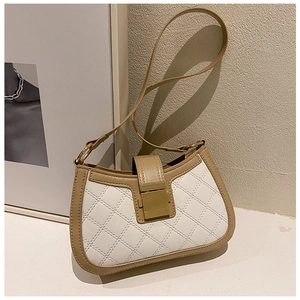 Close-up of beige and white patchwork shoulder bag with quilted pattern and gold buckle