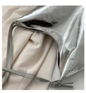 Macro view of metallic silver shoulder bag showing mirror gloss finish and side stitching