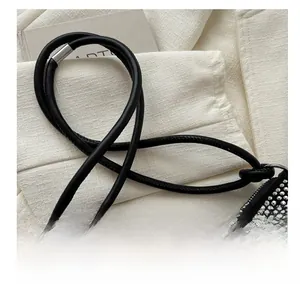 Detailed close-up of a black evening bag featuring silver rhinestones and a round leather handle