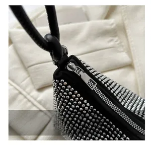 Close-up of a black rhinestone handbag featuring a smooth silver metal zipper and crystal texture