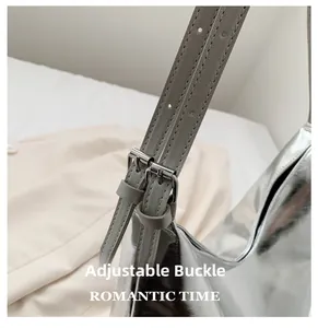 Detail of the adjustable metal buckle and grey strap on a silver metallic tote bag