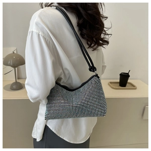 Detail of a sparkling rhinestone hobo bag worn with a white shirt in a minimalist room