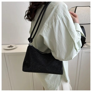 Detail showing the black rhinestone crossbody bag with a knot handle worn by a model