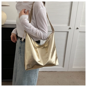 Close-up of golden metallic tote bag with glossy finish on model with knit sweater
