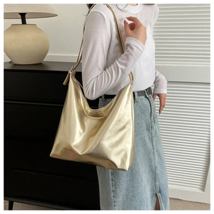 Detail of a large gold tote bag with metallic sheen and slim shoulder strap