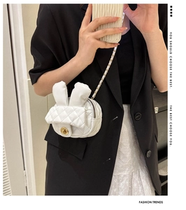 Close-up of white quilted bunny shoulder bag with golden bead lock on model