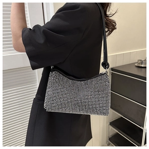 Detailed close-up of a sparkling rhinestone evening bag with black leather shoulder strap