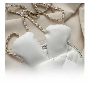 Detail showing white quilted mini bag with bunny ears and woven gold chain strap