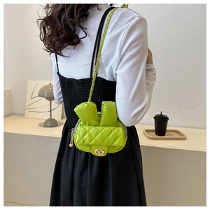Detail of neon green quilted mini bag with bunny ears decoration on a black dress