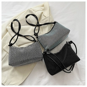 Close-up of sparkling rhinestone hobo bags in silver, blue, and black on a beige blazer