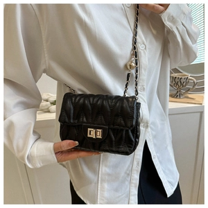 Détail du sac bandoulière matelassé noir avec chaîne dorée et fermoir pivotant sur mannequin