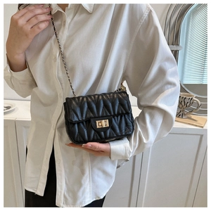 Détail du sac bandoulière noir matelassé avec chaîne dorée et fermoir pivotant en métal
