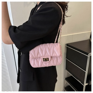 Détail du sac à bandoulière matelassé rose clair avec chaîne dorée et fermoir pivotant