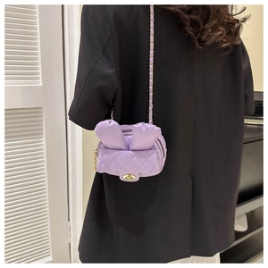 Detail view of purple quilted mini chain bag with cute rabbit ears on model's shoulder