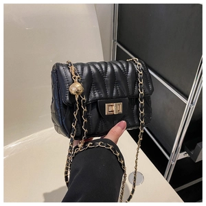 Détail du sac en cuir noir matelassé en V avec fermoir doré et chaîne à boule réglable