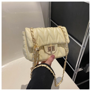 Détail d'un sac bandoulière jaune crème avec texture matelassée en V et fermoir doré